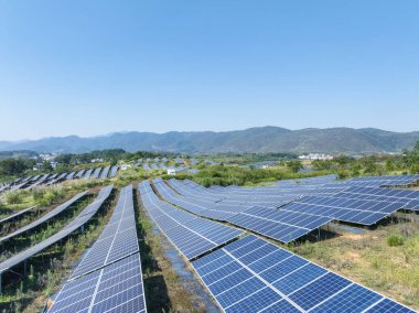 Yamaçtaki güneş enerjisi istasyonunun havadan görünüşü, dağlık bölgede yeşil enerji.