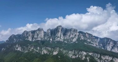 Beyaz bulutların dağ tepelerinin etrafında dönen kayalıklardan yükselişi ve Çin 'in Lushan Dağı' nın güzel doğa manzarası. 