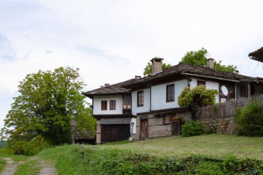 BOZENTSI, BULGARIA - 26 Mayıs 2023: Bulgaristan 'ın Gabrovo bölgesindeki köyün mimari-tarihi rezervindeki eski evlerin bahar manzarası