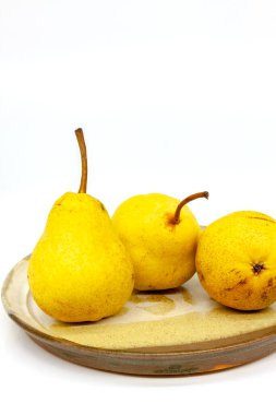 Seramik tabakta sarı armutlar. Sığ alan derinliğine sahip seçici odak.