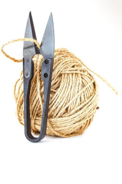 Beyaz arka planda bir makas ve bir sicim topu. Sığ alan derinliğine sahip seçici odak.