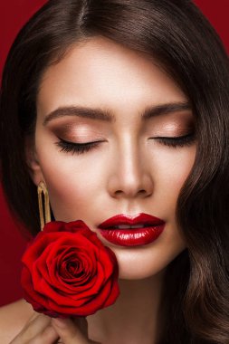 Kırmızı Dudaklı Kadın Makyajı. Güzellik Modeli Göz makyajı Kapalı Gözler 'le yakın çekim. Kadınlar Pürüzsüz Cilt Yüzü Parlatıcı Ruj ile Ve Çenesinde Gül Çiçeği