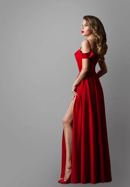 穿红色长裙的时装模特 一个优雅的女人在傍晚时分在格雷上空露宿 性感女孩在Slit展示腿 女人波威卷发风格 女式假日服装 — 图库照片