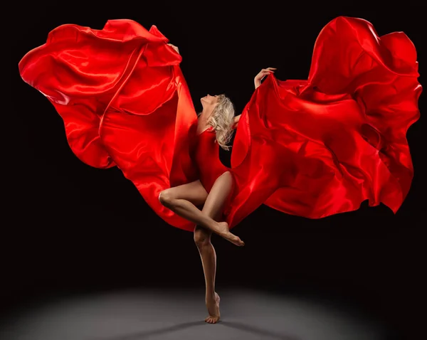 バレエダンサーは 黒の背景の上に風に乗って飛んで赤いシルク生地でジャンプします フローティングスカーフでドレスを振って美しいバレリーナダンス モダンダンスショー — ストック写真