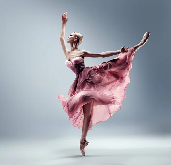 ピンクシフォンのバレリーナはスプリットジャンプドレス 絹のガウンのポイントの靴のバレエダンサー グレーの背景の上にダンスチュチュスカートの優雅な女性 — ストック写真