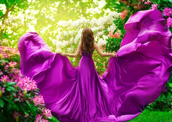 春花公园里穿着紫色丝绸衣服的时尚女人后视镜 粉红缎子中优雅的模特儿在风中飘扬 望着花园子 美丽的女孩享受夏日阳光 — 图库照片