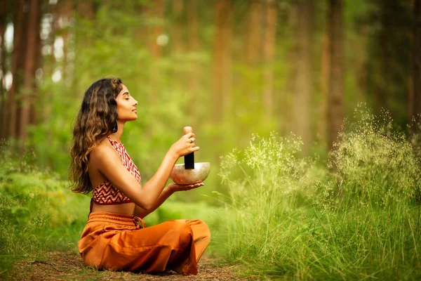 インドの女性は マレットの屋外でチベット語の歌のボールを再生します 瞑想音楽療法とサウンドヒーリングをリラックスさせます 森の中の精神的なヨガ瞑想練習 — ストック写真