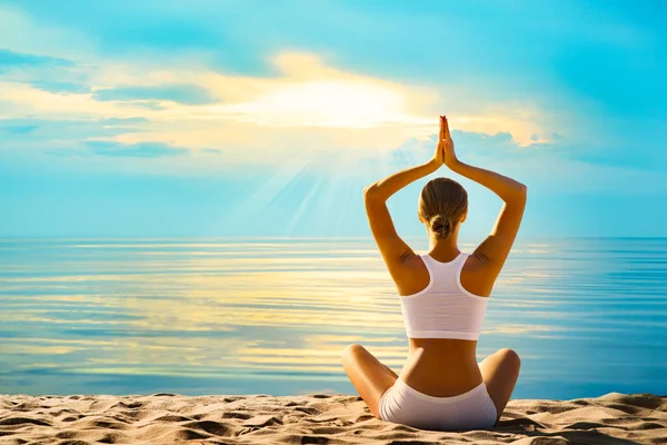 海によるヨガ瞑想 サンセットビーチ屋外で瞑想する女性のリアビュー 女性シルエットでLotus Namaste位置オーバーサンシャインブルースカイ背景 — ストック写真