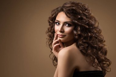 Kıvırcık saçlı güzellik mankeni. Koyu bej yerine uzun dalgalı saçlı genç kadın. Pürüzsüz cilt doğal makyajlı güzel kız.
