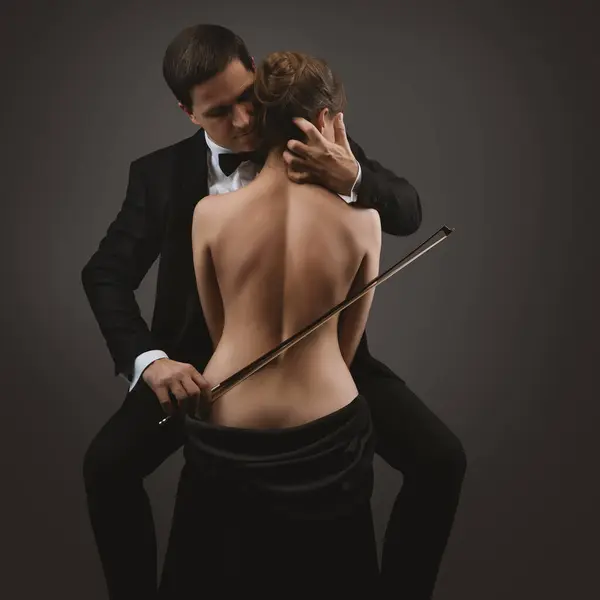 恋爱中的性感情侣拥抱 下跪的男人玩女人性感裸背游戏 女人的身体就像大提琴古典文学浪漫主义音乐艺术家胜过黑人 艺术照片 免版税图库照片