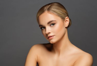 Gri arkaplan üzerinde doğal pürüzsüz deri makyajlı güzellik modeli yüz. Mükemmel Kaşlı ve Dudaklı Güzel Sarışın Kadın Makyajı. Yüz gerdirme Dermal Doldurucu