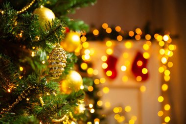 Altın koni süsleriyle süslenmiş Noel ağacının yanında Noel Baba çoraplarıyla parlayan şöminenin üzerinde. Noel Odası Arkaplanı. Xmas Dekorasyonu. Yeni yıl tatil kartı.
