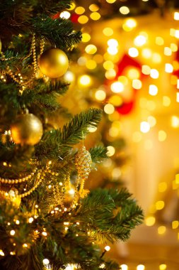 Altın süslerle süslenmiş Noel Ağacı 'nın yakınında. Parlayan Xmas Işıkları Arkaplanı' nın üzerinde. Xmas Odası Dekorasyon ve Çelenk Asma. Yeni yıl tatil kartı.
