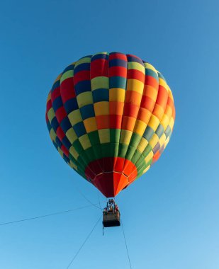 Mavi gökyüzünde süzülen renkli Muticolor sıcak hava balonu.