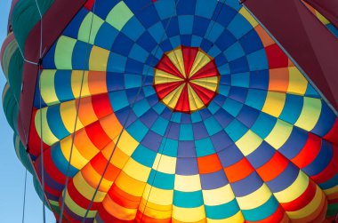 Mavi gökyüzünde süzülen renkli Muticolor sıcak hava balonu.