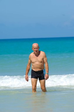 Son sınıftan bir adam yüzmek üzere suyun içinde duruyor. Varadero Küba plajı