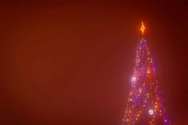 Uitzicht Verlichte Kerstboom Tegen Donkerrode Achtergrond — Stockfoto