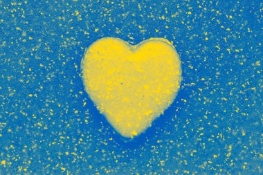 valentine shaped cookie on abstract plastic background colored in colors of Ukrainian flag