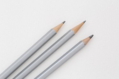 Beyaz kağıt üzerinde duran üç pastel kaleme yakın plan.