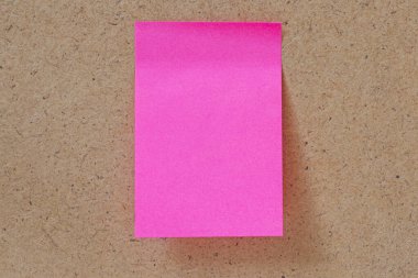 Tahta panoya yapıştırılmış pembe, boş bir not.