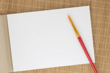 Bambu paspasın üzerinde duran akvaryum için boya fırçasını ve çizim defterini kapat.