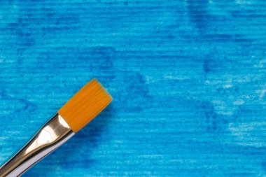 close up of paint brush at paper painted with blue gouache clipart