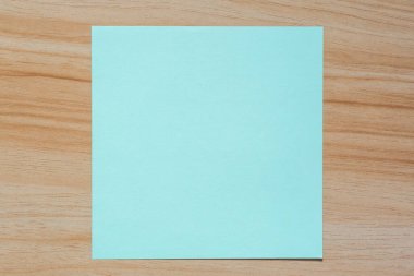 Açık yeşil boş bir kağıt parçasını ahşap masanın üzerine koy.