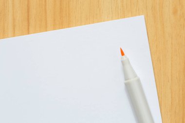 İşaretin ve boş beyaz kağıdın kapağı ahşap masanın üzerinde.
