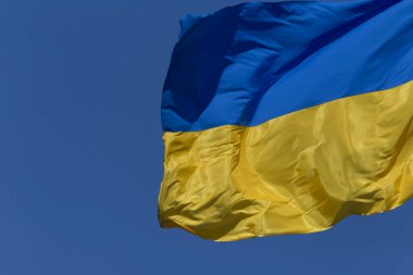 Açık mavi gökyüzüne karşı dalgalı Ukrayna bayrağına yakın plan