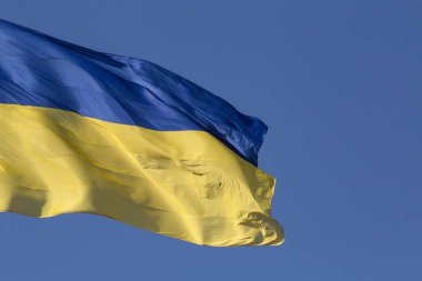 Açık mavi gökyüzüne karşı dalgalı Ukrayna bayrağına yakın plan