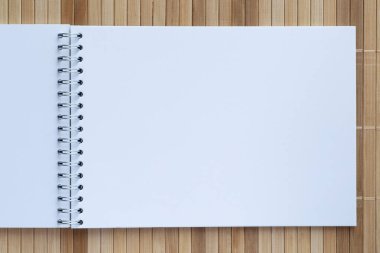 Bambu paspasın üzerinde sarmal klasörle çizim defterinin boş sayfasını kapat