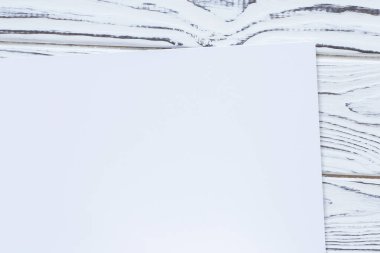 close up of blank white sheet of paper laying on wooden board