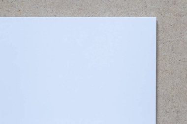 close up of blank white sheet of paper laying on compressed wood board