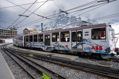 15 Nisan 2022 - Kleine scheidegg, İsviçre: Güneşli bir kış gününde, Jungfraujoch 'tan Kleine Scheidegg' e giden çarklı bir tren arka planda Eiger ve Monch, İsviçre 'de