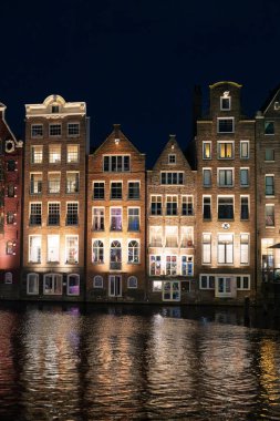 Hollanda, Amsterdam 'da geceleri sulara yansıyan bir dizi aydınlık kanal evi..
