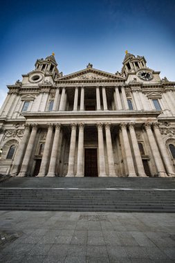 Londra 'daki St. Paul Katedrali' nin çarpıcı alçak açılı görüntüsü neoklasik cephesini ve açık mavi gökyüzünün altındaki karmaşık taş oymalarını gözler önüne seriyor..
