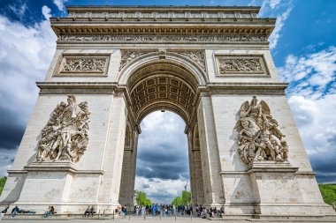Paris 'teki Zafer Takı' nın detaylı bir perspektifi. Karmaşık oymalarını ve anıtsal mimarisini parçalı bulutlu gökyüzünün arka planına karşı sergiliyor..