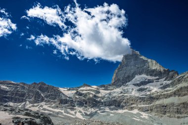 Matterhorn tepesinin göz kamaştırıcı manzarası. Parlak mavi gökyüzünün altında dağınık bulutlar..