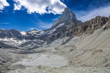 İsviçre 'deki Matterhorn Dağı' nın göz kamaştırıcı manzarası. Buzul gölü ve yürüyüş yapanlar ön planda..