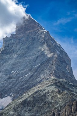 İsviçre Alpleri 'ndeki görkemli Matterhorn dağlarının manzarası kısmen bulutlarla kaplı mavi bir gökyüzü..