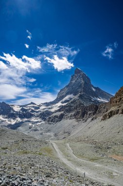 Güneşli bir günde, açık mavi gökyüzü ve dağınık bulutlarla İsviçre 'deki Matterhorn Dağı' nın çarpıcı manzarası..
