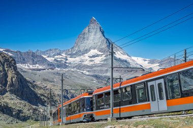 The Gornergrat Bahn train travels with the Matterhorn mountain in the background in Zermatt, Switzerland.