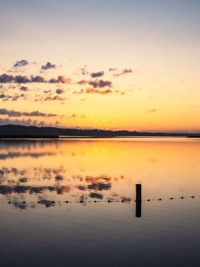 Seedorf, Almanya 'daki Schaalsee gölünde bulutlarla gün doğumu ve yansıma.