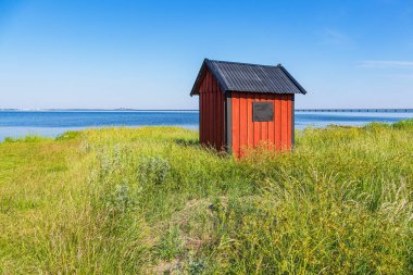 Red wooden fishing hut on shore of the Baltic Sea on the island Oeland in Sweden. clipart