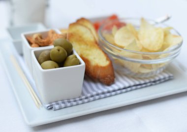 Yeşil zeytin, kızarmış ekmek ve aperatif olarak beyaz tabakta çizgili peçete, çok seçici bir odak noktası var.