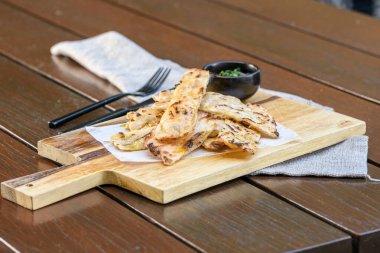 Chargrilled housemade flatbread served with a side of herb dip in a black bowl clipart