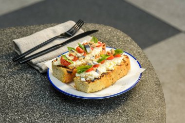 Housemade focaccia bruschetta topped with cherry tomatoes, ricotta, fresh basil, and anchovies clipart