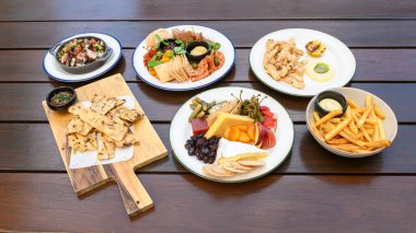 Izgara ahtapot salatası, şarküteri tahtası, aioli soslu kızarmış kalamar soslu ev yapımı ekmek, peynir tabağı ve biftek kızartması da dahil olmak üzere çeşitli gurme yemekleri.