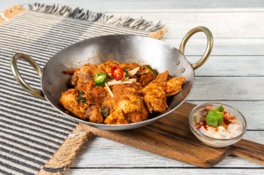 Yeşil biber, zencefil ve kişniş ile süslenmiş baharatlı köri soslu tavuk. Mükemmel bir yemek deneyimi için küçük bir tabak yoğurt sosunun yanında geleneksel bir kasede servis ediliyor..