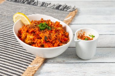 Taze otlarla süslenmiş ve yanında küçük bir porsiyon kremalı yoğurt ile servis edilen aromatik baharatlar ve taze etle dolu lezzetli bir kase biryani. Limon dilimi lezzet katar.